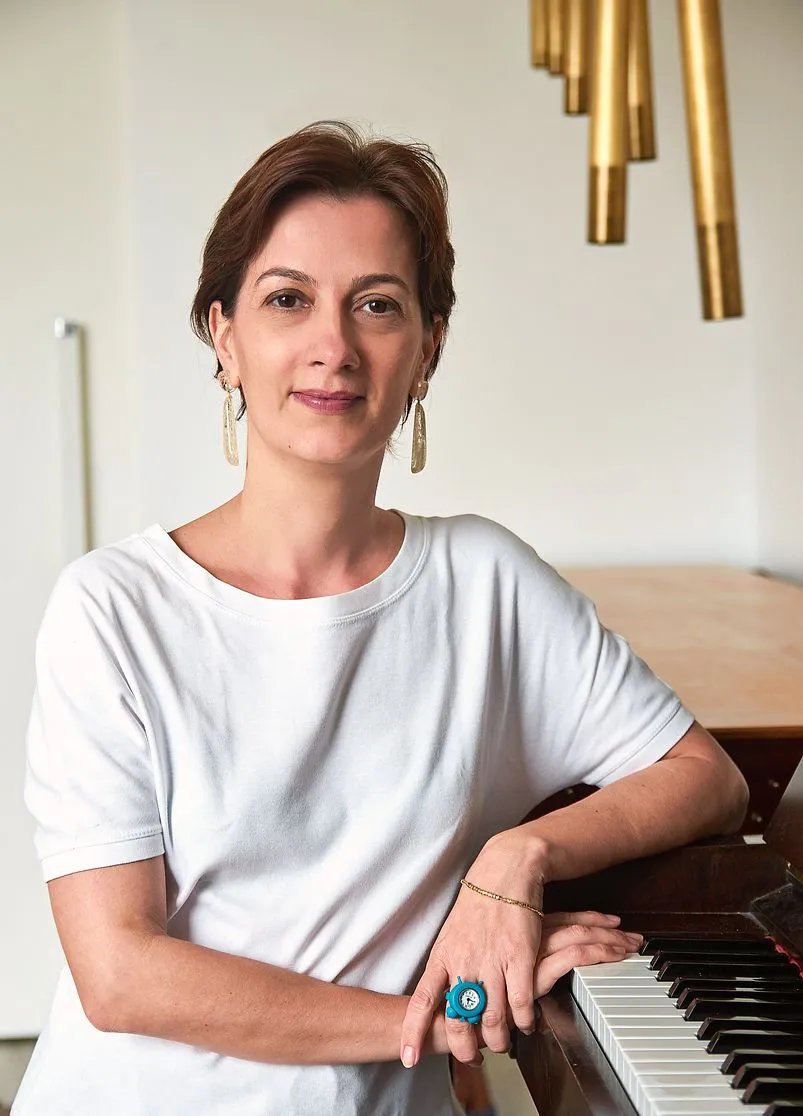 Suzana Brunhara apoiada ao piano do consultório